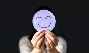 woman holding up a drawing of a smiley face