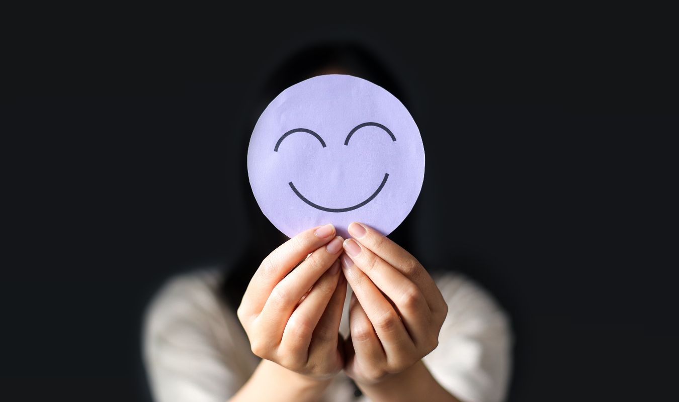 woman holding up a drawing of a smiley face