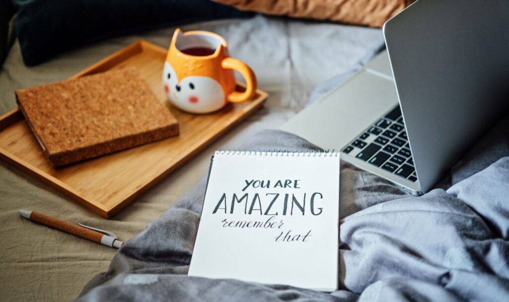 Positive affirmation note beside a cozy workspace and tea, symbolizing calming affirmations for anxiety and self-support.