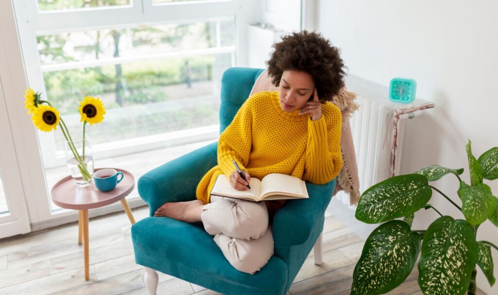 Woman journaling in a bright cozy space, practicing affirmations for success and positive mindset habits.