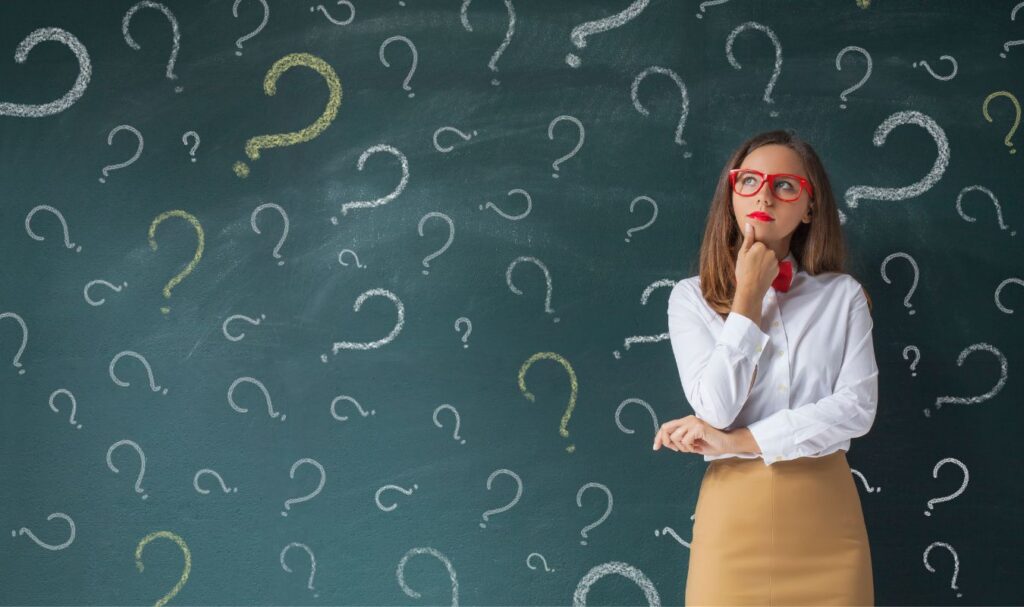 Woman thinking in front of question marks while learning how to manifest money and shift limiting beliefs