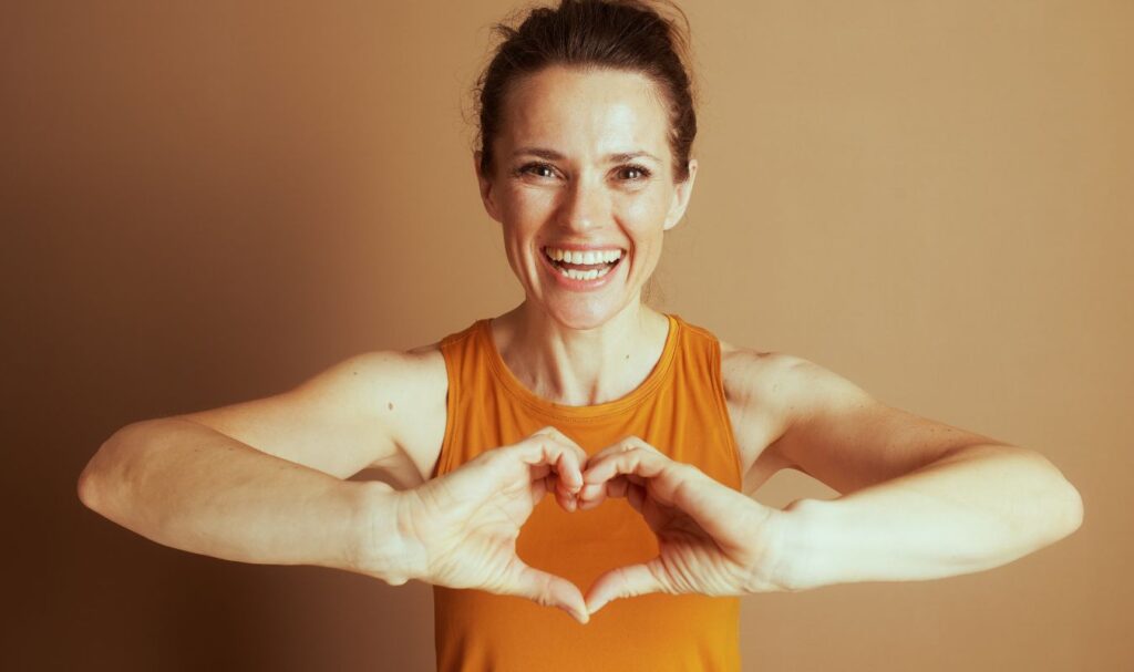 A woman holding her hands in the shape of a heart, symbolizing a loving kindness meditation practice