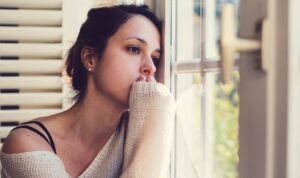 Depressed woman looking though the window