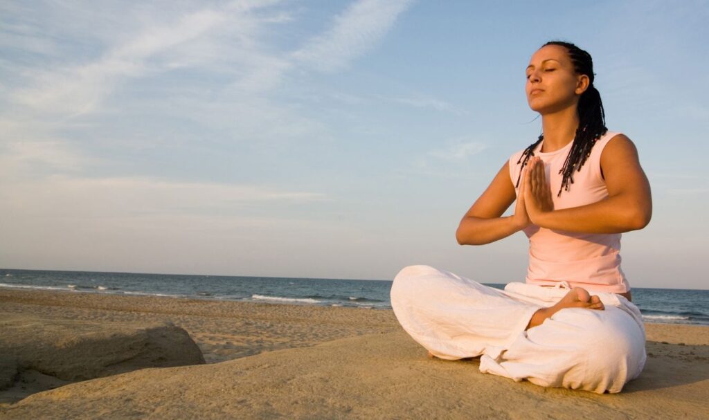 Woman meditating on the beach to strengthen the subconscious mind and manifestation practice