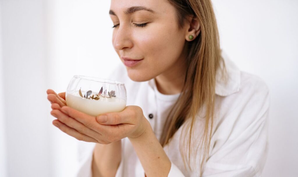 young woman smelling a candle, feeling happy that she's been able to clear her brain fog