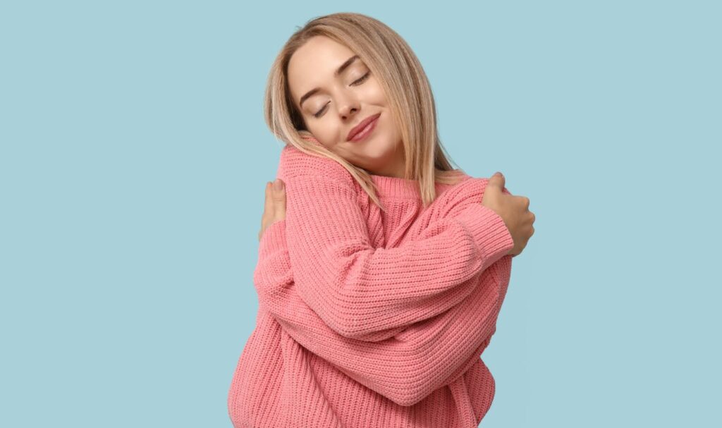 Woman hugging herself with eyes closed, representing self-love and emotional alignment while manifesting a specific person.