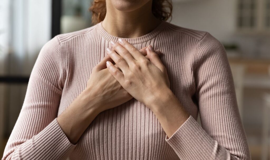 woman holding her hands over her heart, practicing gratitude for the integration she's done through shadow work