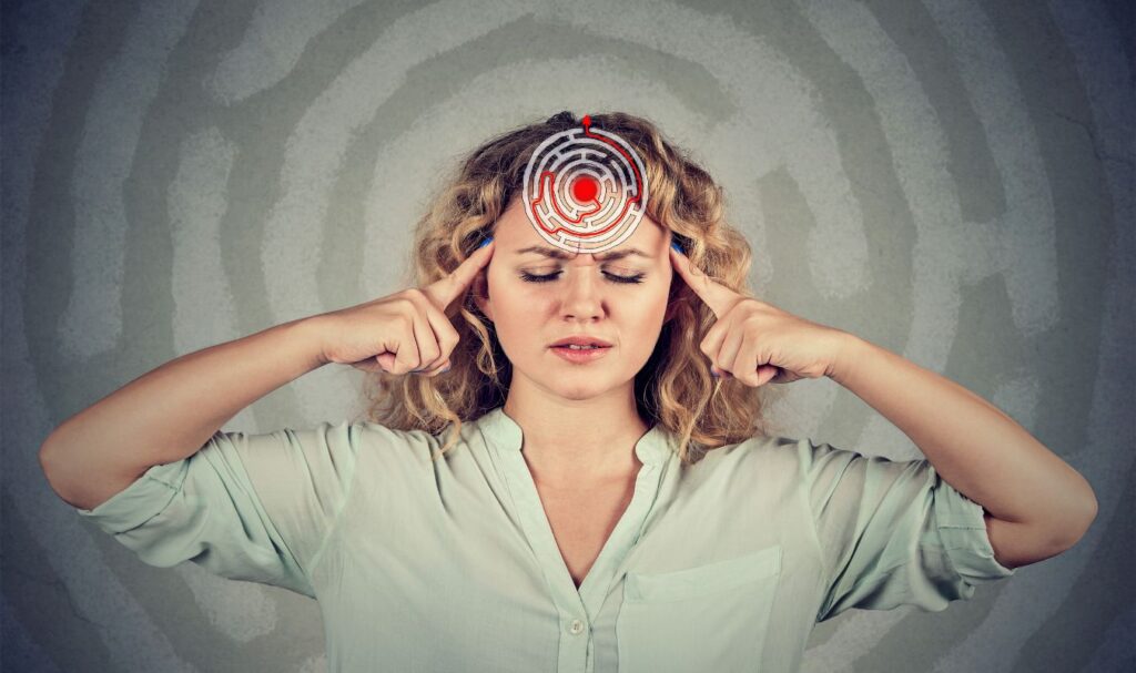 woman holding her head in pain showing that she has trouble controlling the subconscious mind